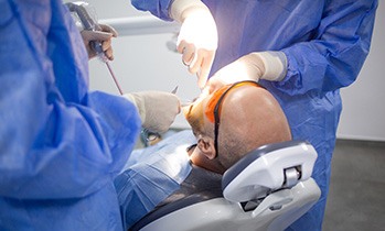 Dentists in blue scrubs performing patient’s procedure
