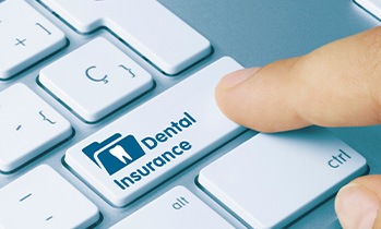 Finger pressing “dental insurance” button on keyboard