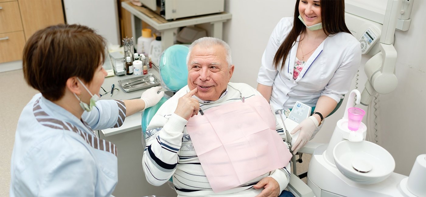 Man in dental chair pointing to cheek