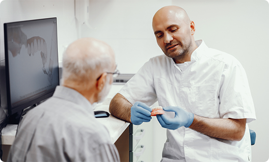 Male dentist showing male patient dentures