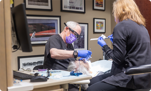 Two dentists treating a patient