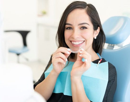 Happy dental patient holding CandidPro clear aligner 
