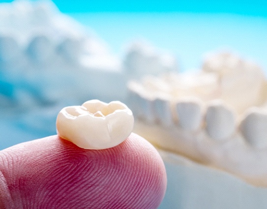 Closeup of dental crown in Little Rock on finger