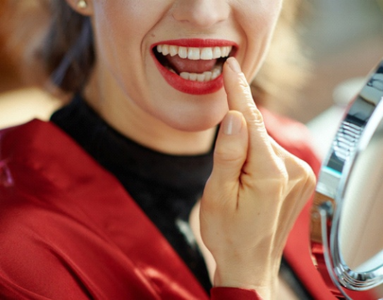 Woman smiling and pointing to her dental crown in Little Rock