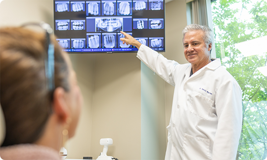 Dentist showing patient X rays on a monitor