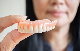 A closeup of a removable denture held by a woman