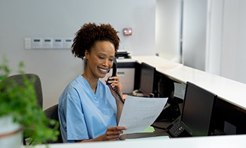 a front desk staff member talking on the phone to a patient