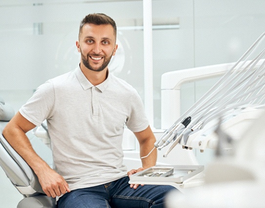 Man in grey polo shirt smiling while sitting in dental chair