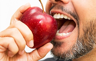 An up-close look at a person preparing to bite into a whole apple