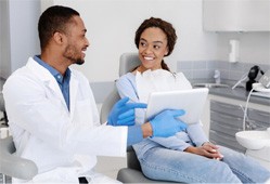 Dentist smiling at patient while reviewing information on tablet