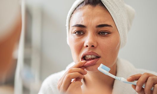 A woman looking at her lip in the mirror