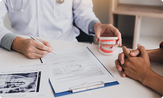 Dentist filling out form on clipboard and holding model teeth
