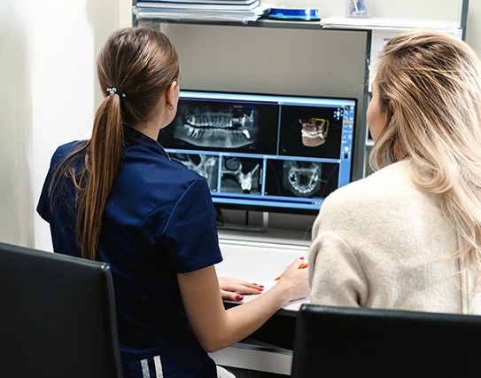 Dentist and dnetal team member looking at digital x-rays on chairside computer