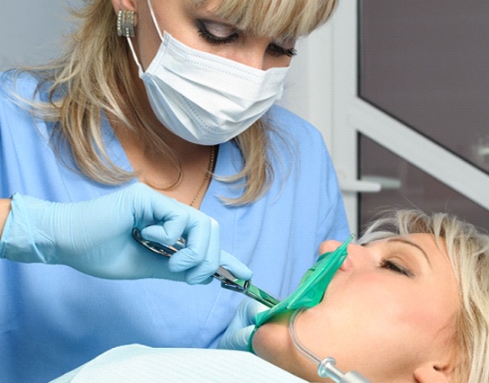 A dentist performing wisdom teeth removal on a female patient