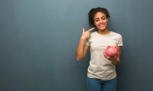 A patient smiling and holding a piggy bank.