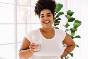 a woman smiling and holding a glass of water