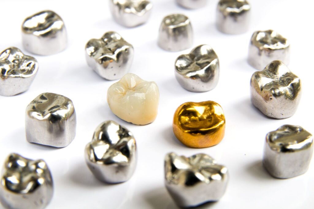 Porcelain and gold dental crowns surrounded by silver metal ones