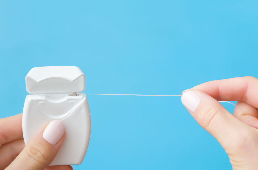 Hand pulling dental floss out of dispenser