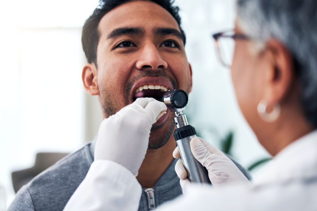 Dentist screening patient's mouth for signs of oral cancer